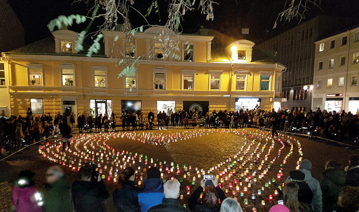 Ljuslyktor brinner på Lilla torget en mörk kväll. Många människor har samlats för att titta på.
