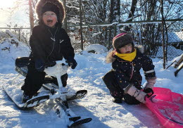 Pojke och flicka åker snowracer och pulka