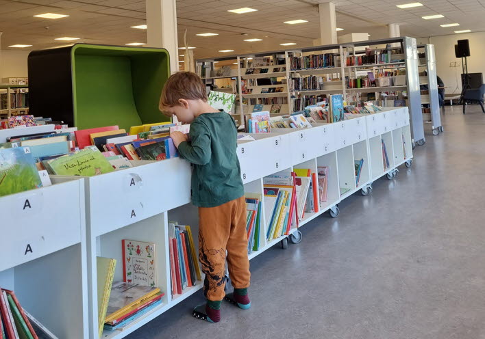 pojke bläddrar bland böcker på biblioteket