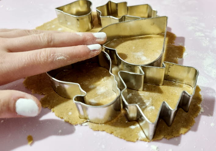 En hand trycker in pepparkaksformar i pepparkaksdegen.
