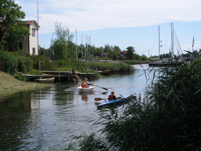 Två kanotister på Norrån i Figeholm, gästhamnen i bakgrunden.