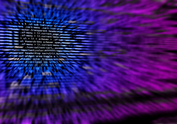 Bilden går i blå och lila toner med HTML-kod skriven över hela ytan med skärpa på en del av koden resten oskarpt.
