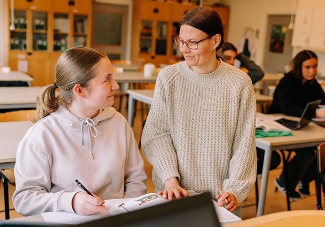 En lärare hjälper sin elev i klassrummet.