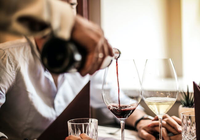 Servitören häller i vin i ett glas.