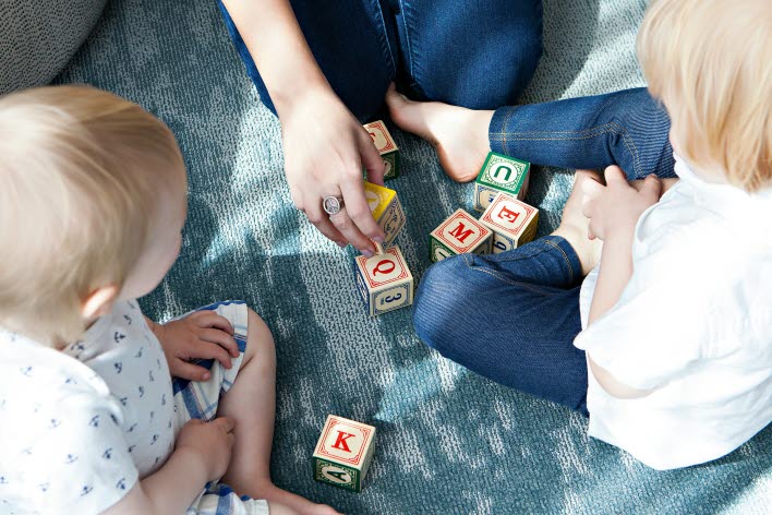 mamma och två barn sitter på golvet och bygger med klossar