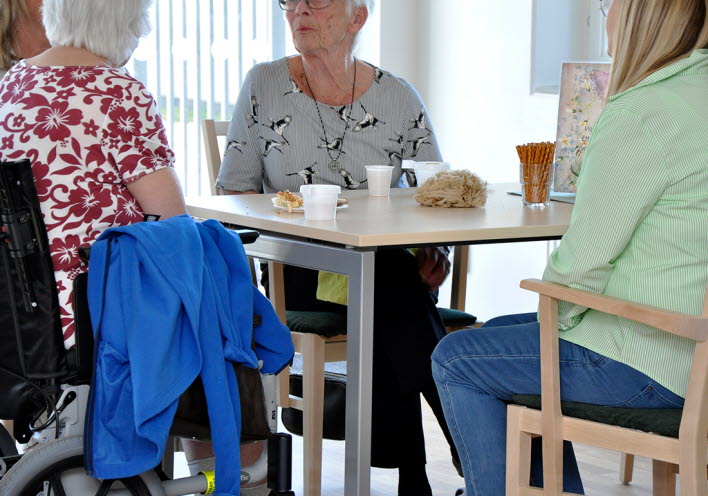 Några äldre damer sitter vid ett bord och fikar.