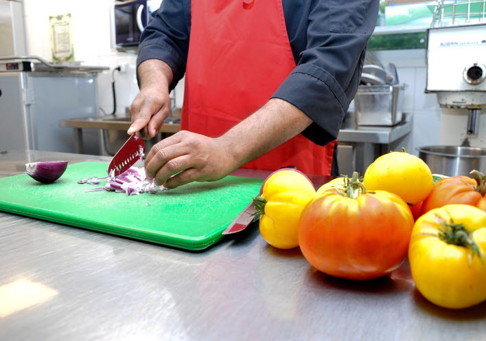 Närbild på en kock som hackar grönsaker.