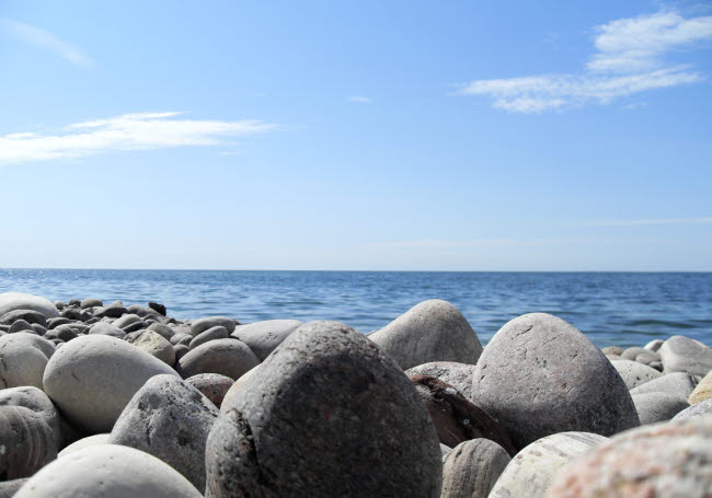 Havsstrand med stenar i förgrunden och havet i bakgrunden